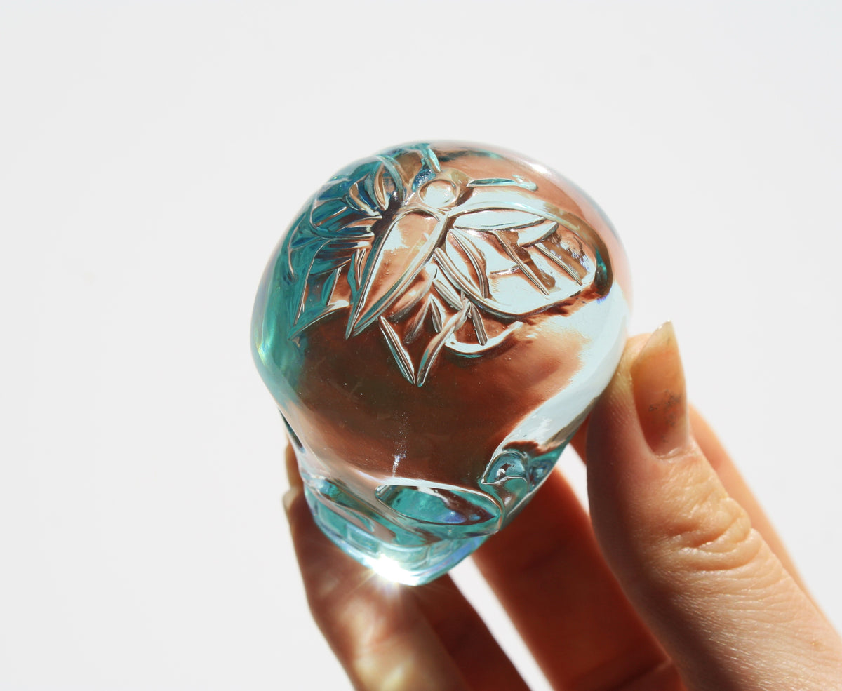 Blue obsidian crystal skull with hand‑engraved butterfly designs by artisan Vikas Meena.